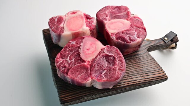 Meat preparation showcasing fresh cuts of osso buco on a wooden board