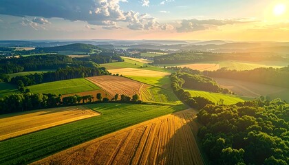 Obraz premium Aerial view of sunlit patchwork farmland at sunset