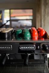 Colourful cups of coffee on top of the espresso machine.