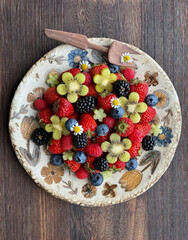 Delightful floral feast of vibrant berries on antique plate, capturing Midsummer's Eve's bounty and Dia de los Muertos vibrancy