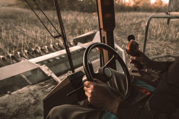 The combine operator drives the combine harvester, harvesting sunflowers in the field. View from the driver's cab.