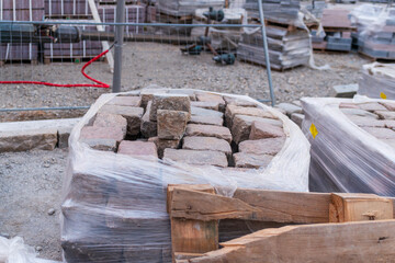 A large bundle of paving stones tightly wrapped in plastic awaits use at a construction site. The image highlights raw materials and the organized preparation needed for city renovation projects.
