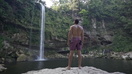 Captured in the gentle light of a bright morning, a man stands on a rock at the base of the majestic Misol-Há waterfall in Chiapas, México.
