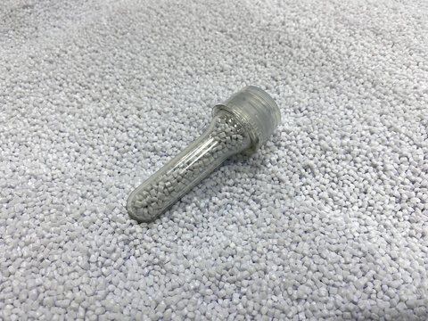 Bottle parison or PET preform on heap of PET homopolymer granules. Test or tube. Virgin polyethylene terephthalate. Granulated plastic polymer