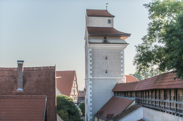 Blick auf historische Altstadt in Nördlingen und das Reimlinger Tor mit Turmwächterstube und überdachte umlaufende Stadtmauer mit Wehrgang an tiefstehender Sonne