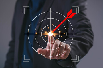 Businessman touching virtual target with dart hitting bullseye, symbolizing business goals,...