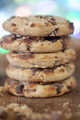 Stacked double chocolate Cookies, crumbling on a rustic wooden chopping board  