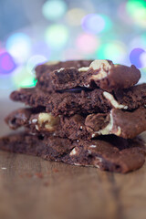 Stacked double chocolate Cookies, crumbling on a rustic wooden chopping board  
