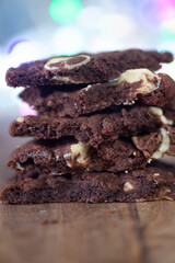 Stacked double chocolate Cookies, crumbling on a rustic wooden chopping board  