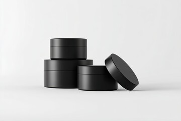Three black cosmetic jars in a studio setting.  Stacked and slightly offset, displaying various sizes.  Clean, simple design
