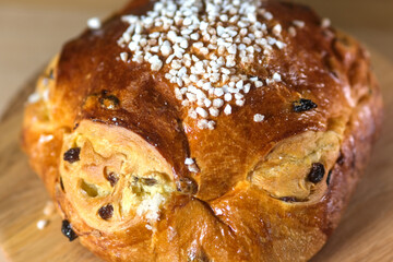 Golden raisin brioche with pearl sugar topping on a wooden board, a traditional sweet bread from...