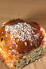 Golden raisin brioche with pearl sugar topping on a wooden board, a traditional sweet bread from northern France.