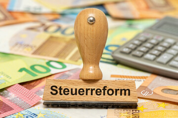 Ein Holzstempel ist beschriftet mit dem Aufdruck Steuerreform als Symbolbild für notwendige...