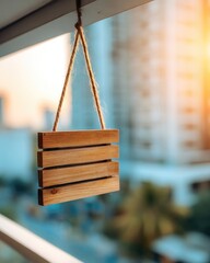 A light brown wooden sign, hanging from a balcony, against a blurry cityscape