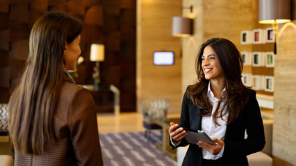 Hotel staff welcoming guest in lobby, offering professional service and hospitality at reception...
