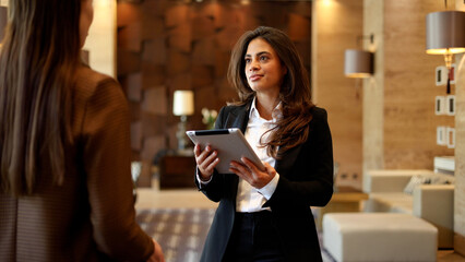 Businesswoman holding tablet, discussing corporate strategy during a professional meeting in a modern office lounge
