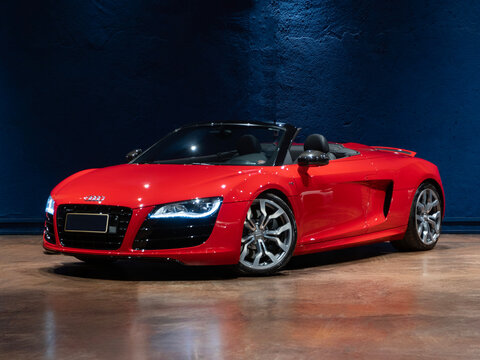 Red Audi R8 Spyder V10 in a blue studio, German convertible supercar front quarter view

