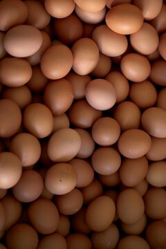 A close-up of numerous brown eggs stacked closely together.