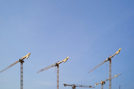 Four construction cranes against a clear blue sky. Berlin, Germany