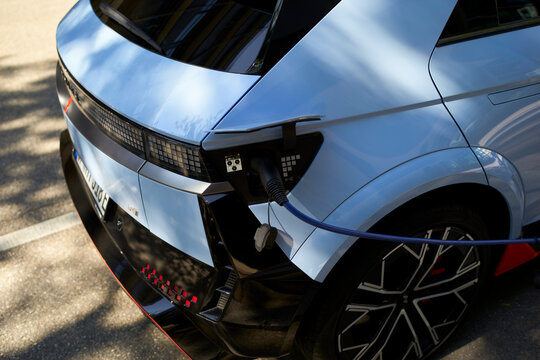 Stylish electric car charging in bright sunlight on paved street. Stuttgart, Germany