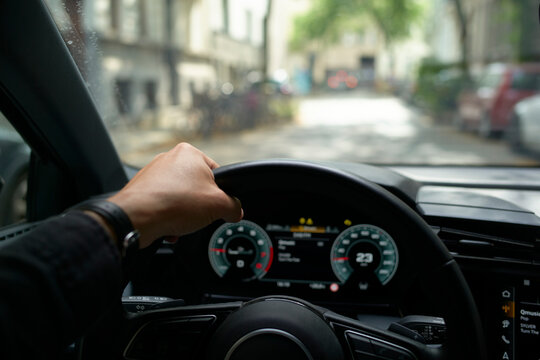 Hand on steering wheel, driving through a blurry, sunlit city street. Germany