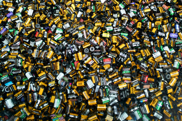 Pile of assorted 35mm film canisters in various colors and brands spread across a surface.