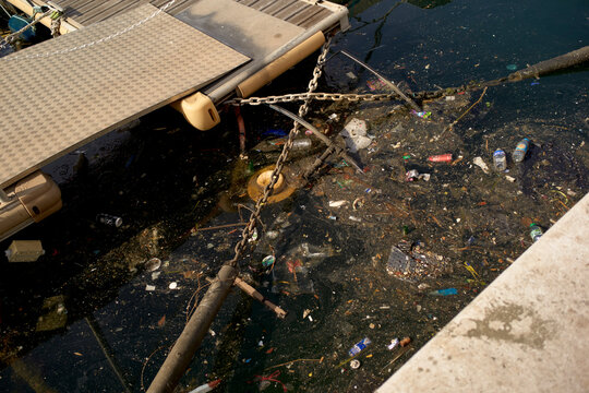 Polluted water near a dock with trash and debris floating on the surface Marseille, France