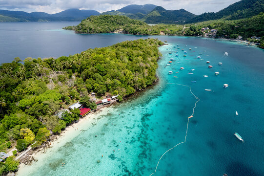 Aerial view of tropical island with lush greenery, turquoise water, and scattered boats. Sabang, Aceh, Sumatra, Indonesia