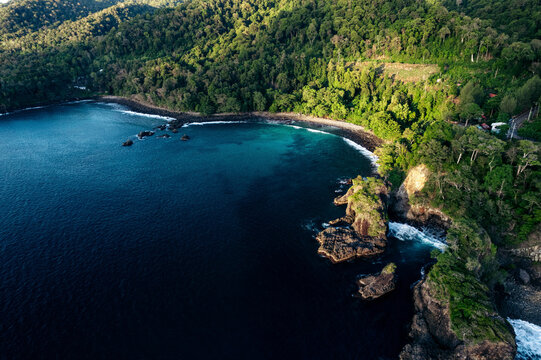 Aerial view of a lush green coastline with rugged cliffs and deep blue ocean. Paya, on We Island in Aceh, Sumatra, Indonesia