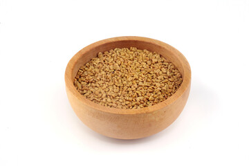 Fenugreek seeds in wooden bowl on white background