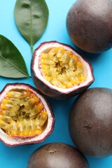 Fresh passion fruits with green leaves on light blue background, above view