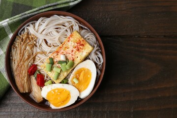 Tasty ramen with enoki mushrooms in bowl on wooden table, top view. Space for text