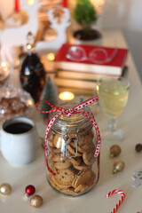 Cookie jar, tea, wine, nuts, books, lit candles and Christmas decorations on the table. Cozy Christmas hygge at home. Selective focus.