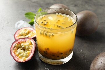 Tasty passion fruit drink with mint, ice cubes and fresh fruits on grey table, closeup