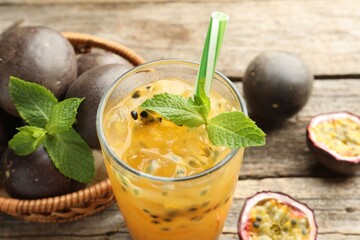Tasty passion fruit drink with mint and fresh fruits on wooden table, closeup