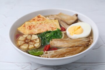Tasty ramen with enoki and king oyster (eryngii) mushrooms on white table, closeup