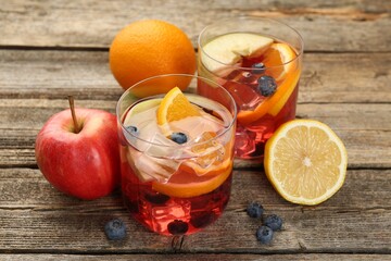 Tasty punch in glasses and fresh fruits on wooden table, closeup. Refreshing drink