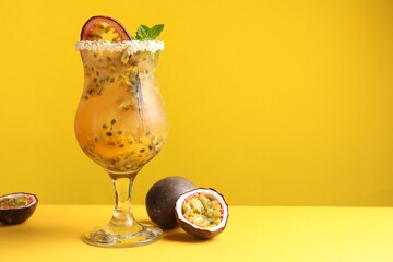 Tasty passion fruit drink with mint in glass and fresh fruits on yellow background. Space for text