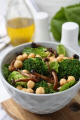 Delicious salad with shimeji mushrooms, chickpeas and broccoli in bowl on table, closeup