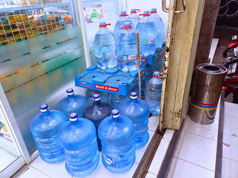 Denpasar, Indonesia - August 20, 2025: Stacks of large bottled water gallons from brands Le Minerale and AQUA ready for sale at a local shop in Indonesia.