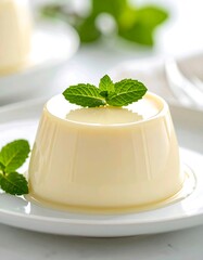 A delicate and creamy individual dessert, featuring a silky-smooth texture, beautifully garnished with fresh vibrant mint, offering a refreshing sweet indulgence