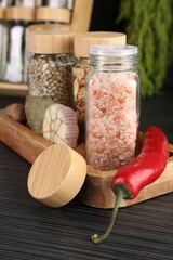 Different spices and glass jars on grey wooden table, closeup