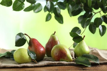 Fresh ripe pears with green leaves on wooden table
