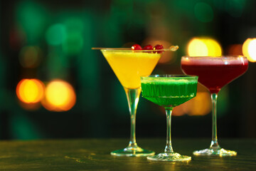 Glasses of alcoholic cocktails on table against blurred background. Space for text