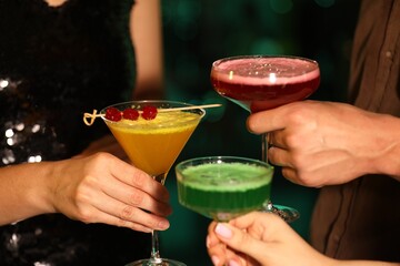 Friends clinking glasses with cocktails in bar, closeup