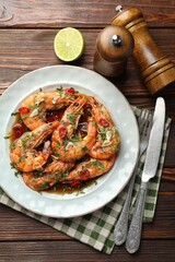 Tasty grilled shrimps with spices, sauce and cutlery on wooden table, flat lay. Delicious seafood dish