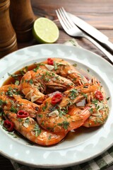 Tasty grilled shrimps with spices, sauce and cutlery on wooden table, closeup. Delicious seafood dish