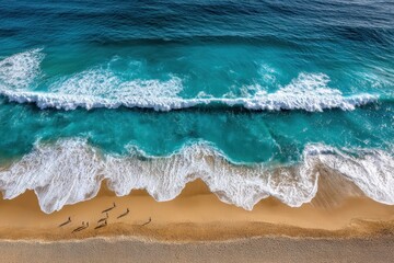 Breathtaking aerial view capturing the contrast of deep turquoise ocean waves crashing onto a golden sandy beach with people.