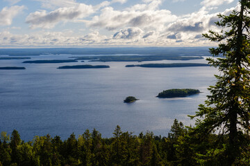 Explore the stunning panorama of Koli National Park, where tranquil waters meet lush forests. The clear skies and scattered islands create a perfect escape into nature.