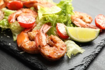 Tasty grilled shrimps with salad on black table, closeup. Delicious seafood dish
